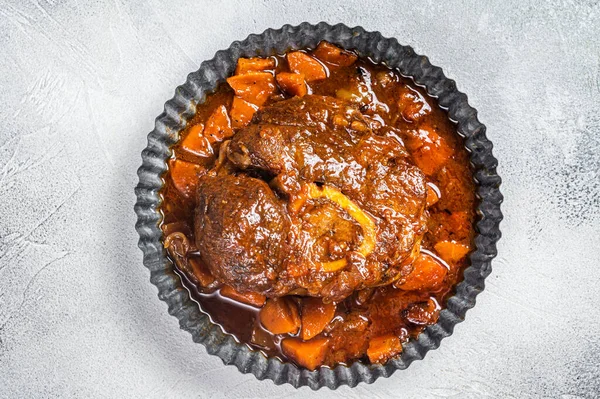 Braised meat on the bone Osso Buco in tomato sauce, veal italian meat Ossobuco. White background. Top view. Copy space.