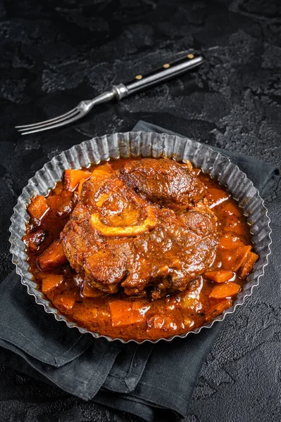 Braised meat on the bone Osso Buco in tomato sauce, veal italian meat Ossobuco. Black background. Top view.