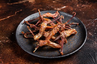 Spicy Dip fried duck tongue. Dark background. Top view.