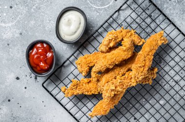 Dip fried Chicken Steak Fingers strips with sauces. Gray background. Top view.