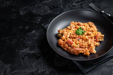 Türk Menemen, domatesli yumurta, yeşil biber ve yeşil soğan. Siyah arka plan. Üst Manzara. Boşluğu kopyala.