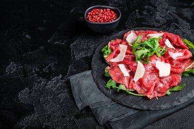 Arugula ve parmesan peynirli biftek carpaccio. Siyah arka plan. Üst Manzara. Boşluğu kopyala.