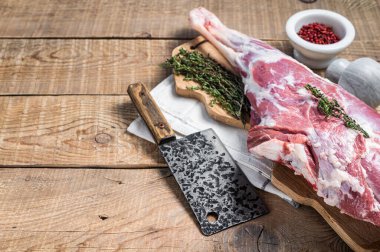 Butcher board with Raw lamb mutton leg with herbs. Wooden background. Top view. Copy space.