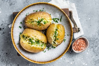 Baked Jacket potatoes with cheese and butter. Gray background. Top view.