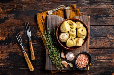 Appetizer Artichoke hearts pickled in olive oil with herbs and spices Wooden background. Top view.