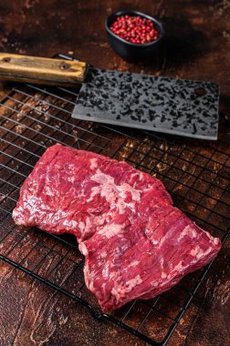 Raw skirt beef steak on meat cleaver. Black background. Top view.