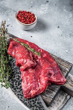 Skirt or Machete beef steak, raw meat with herbs and spices. Gray background. Top view.