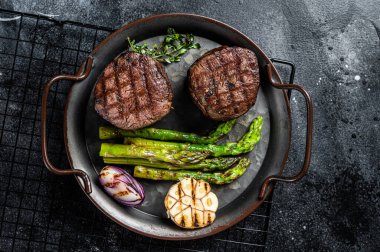 Grilled Fillet Mignon Steak with roasted asparagus. Black background. Top view. clipart