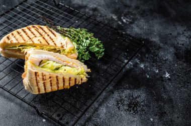 Grilled panini with Prosciutto ham, salad and cheese. Black background. top view. copy space.
