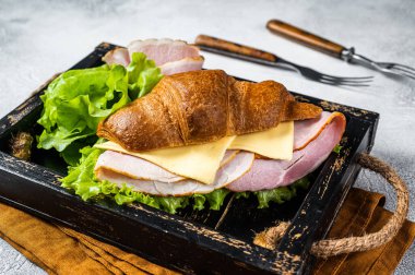 Fresh croissant sandwich with ham, cheese and salad leaf. Gray background. Top view.