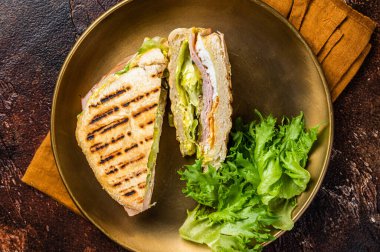 Sliced panini with ham, salad and cheese. Dark background. top view.