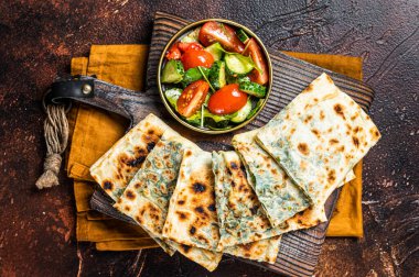 Freshly baked Turkish Gozleme, flatbread with greens and cheese. Dark background. Top view.