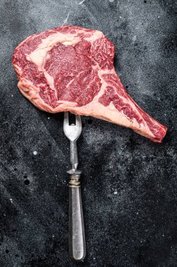 Çiğ kovboy bifteği, kemikli kaburga bifteği, kasap kesim tahtasındaki et mermeri. Siyah arka plan. Üst görünüm.