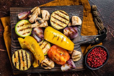 Summer BBQ with grilled Vegetables, bell pepper, zucchini, eggplant, onion and tomato on a wooden board. Dark background. Top view.
