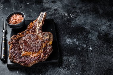 Grilled cowboy or rib eye with bone beef steak. Black background. Top view. Copy space.