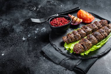 Izgara Urfa kebabı, domates, salata ve soğanlı. Siyah arka plan. Üst Manzara. Boşluğu kopyala.