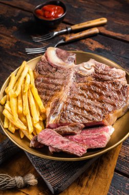 Kızarmış İtalyan Floransalı ya da biftekli biftek ve patates kızartması. Ahşap arka plan. Üst görünüm.