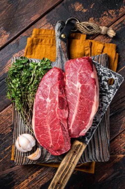 Dry aged Raw top blade beef meat steaks. Dark background. Top View.