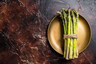 Bunch of Organic green asparagus in a plate. Dark background. Top view. Copy space.