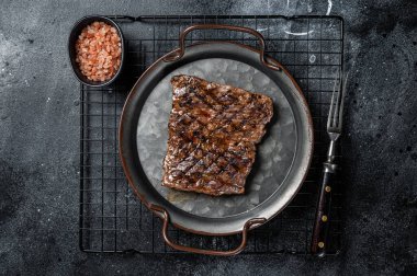 Alternative choice steak - Grilled Skirt or Machete beef meat. Black background. Top view.