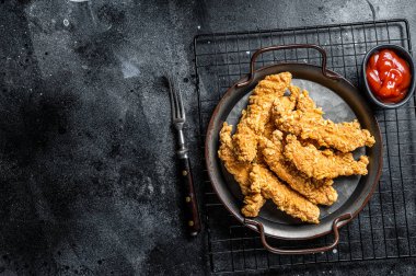 Crispy chicken tenders strips with Ketchup. Black background. Top view. Copy space.
