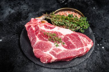 Pork loin steak, raw neck meat with thyme and salt. Black background. Top view.