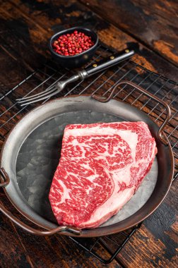 Raw wagyu rib eye beef meat steak in steel tray. Wooden background. Top view.