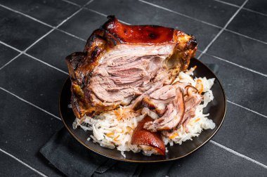 Roast Pork Ham Hock, knuckle with Sauerkraut on a plate. Black background. Top view.