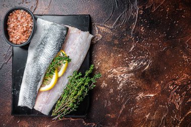 Deniz levreği fileto, kekik ile çiğ deniz balığı, mermer tahtada pembe tuz ve limon. Karanlık arka plan. Üst Manzara. Boşluğu kopyala.