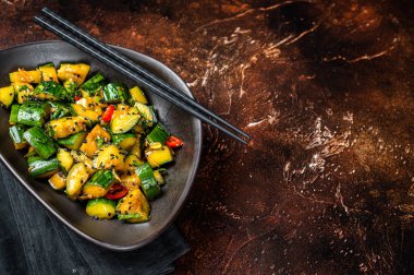 Chinese smashed cucumbers with herbs and sesame oil. Dark background. Top view. Copy space.