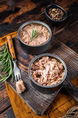 Can with Conserved tuna fillet meat. Wooden background. Top view.