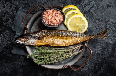 Baked Mackerel Scomber fish in steel tray with thyme and lemon. Black background. Top view.