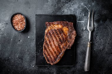 Grilled wagyu Rib Eye steak, marbled beef meat with salt. Black background. Top view.