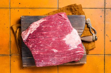 Whole piece of raw Beef Brisket meat. Orange background. Top view.