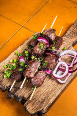 Shish kebab with beef and lamb meat, onion and herbs on Skewers. Orange background. Top view.