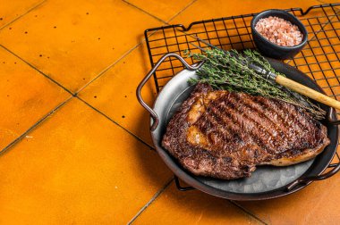 Barbekü ızgara wagyu pirzola bifteği ve çelik tepside otlar. Turuncu arka plan. Üst Manzara. Boşluğu kopyala.