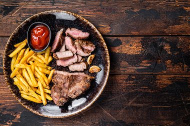 Kızarmış barbekü domuz pirzolası biftek ve patates cipsi. Ahşap arka plan. Üst Manzara. Boşluğu kopyala.