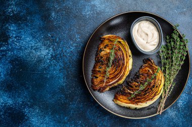 Siyah tabakta soslu kızarmış lahana bifteği. Mavi arka plan. Üst Manzara. Boşluğu kopyala.