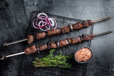 Cooked on the grill beef shish kebab with vegetables and spices, grileld meat. Black background. Top view.