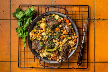 Spanish cocido Madrid stew with chickpeas, meat, carrots and potatoes. Orange background. Top view.