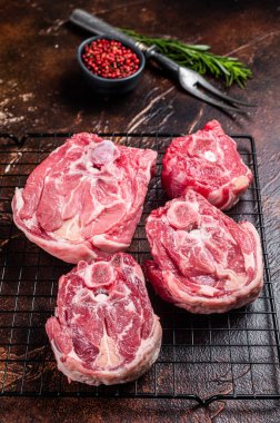 Fresh Raw lamb neck meat slices, mutton meat on a rack with herbs. Dark background. Top view.