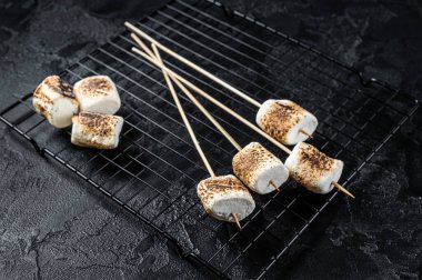 BBQ Grilled Marshmallow on the sticks. Black background. Top view.