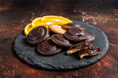 Stack of Chocolate Covered Round Jaffa Cookies with Orange Flavored Marmalade. Dark background. Top view.