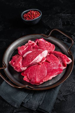 Raw Lamb leg steaks on butcher table. Black background. Top view.