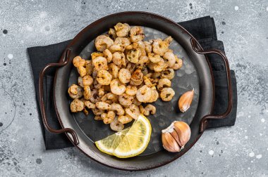 Grilled Shrimps prawns with garlic, olive oil and lemon in a tray. Gray background. top view.