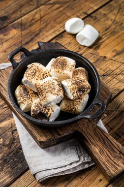 Toasted Marshmallow on open campfire in a skillet. Wooden background. Top view.