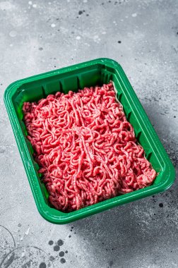 Raw Minced Meat in a Plastic Container, ground beef. Gray background. Top view.