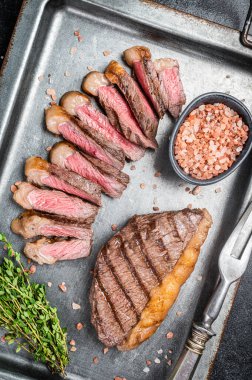 Kızarmış ve dilimlenmiş Top sığır filetosu bifteği, ızgara biftek çelik servis tepsisinde baharatlı biftek. Siyah arka plan. Üst görünüm.
