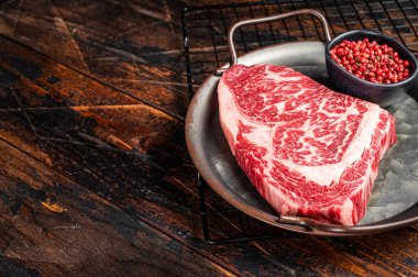 Raw wagyu rib eye beef meat steak in steel tray. Wooden background. Top view. Copy space.