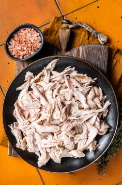 Shredded chicken meat in a plate. Orange background. Top view.